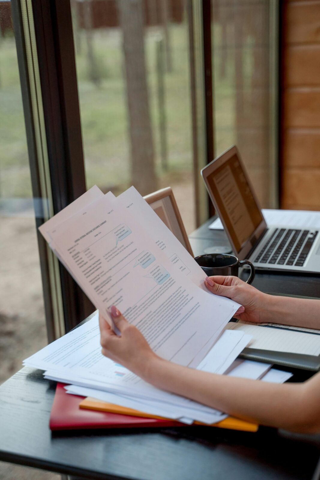 Woman reviewing legal paperwork with laptop and coffee